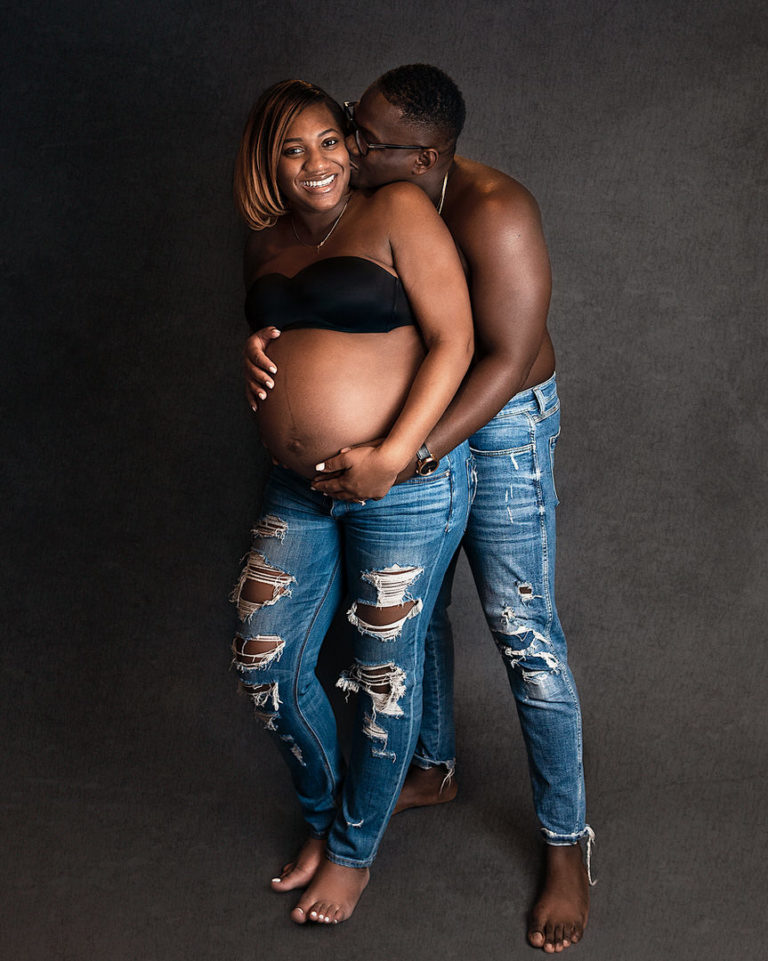 Calgary couples maternity portrait in studio. Shirtless and holding each other smiling.